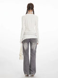 Back view of a model in a white long sleeve top and grey jeans.