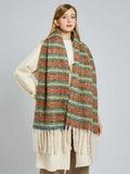 Woman wearing a long, wide scarf with horizontal stripes in rust, light blue, and green, featuring cream fringe at the ends.