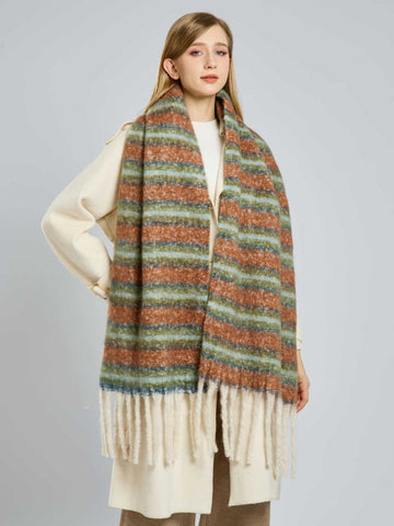 Woman wearing a long, wide scarf with horizontal stripes in rust, light blue, and green, featuring cream fringe at the ends.