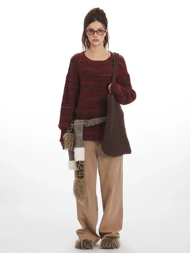 Woman wearing a maroon and brown striped oversized knit sweater with a crew neckline and long sleeves. Main image