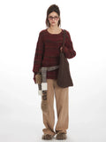 Woman wearing a maroon and brown striped oversized knit sweater with a crew neckline and long sleeves.