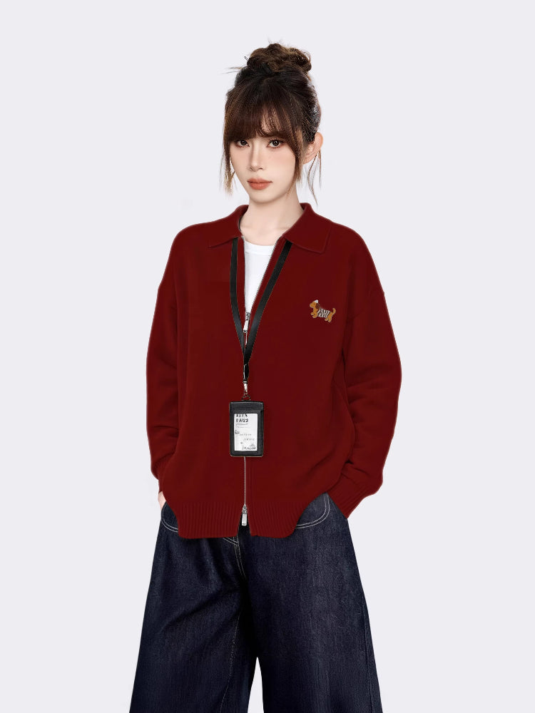 Woman wearing a red knit zip-up jacket with a collared neckline and embroidered graphic on the left chest.