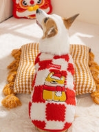 Back view of a corgi dog wearing a red and white checkerboard plush dog coat with embroidered brand logo and festive character.