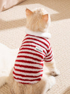 Rear view of a cat wearing a red and white striped fleece pet jacket with a white collar and a "Babby & Me" label.