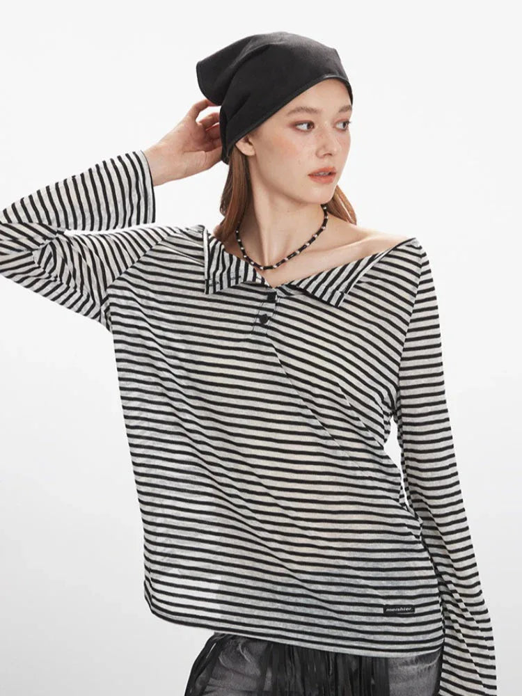 woman touching her hair while wearing a black and white striped long-sleeve shirt with a wide collar