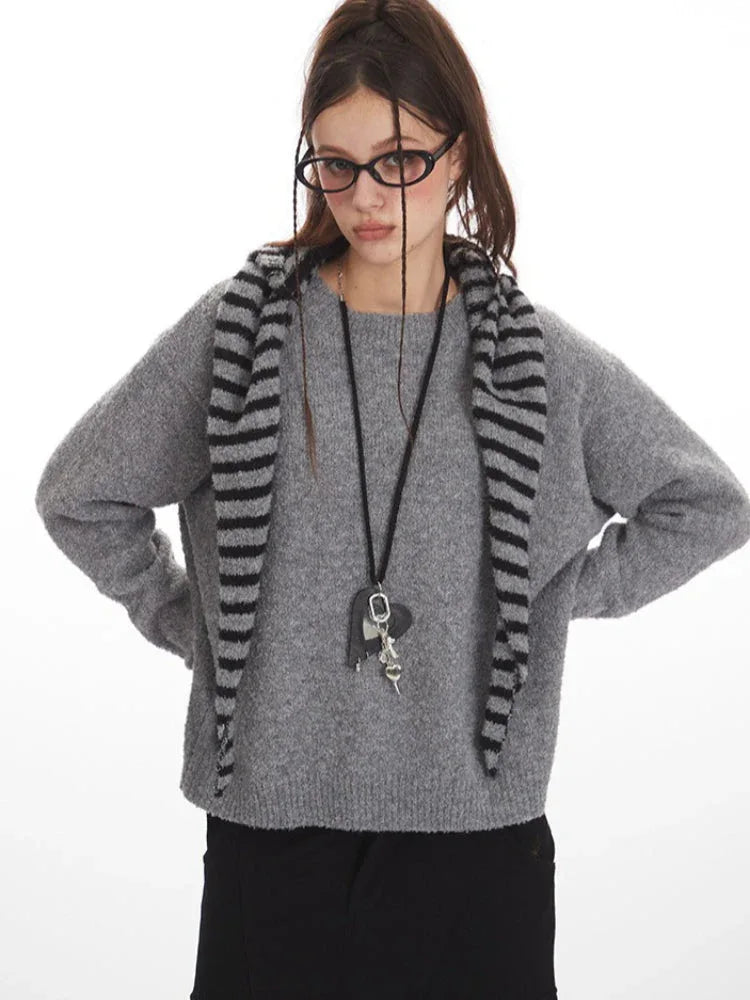 Woman posing with hands on hips in a grey crew neck sweater and black cargo pants