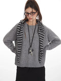 Woman posing with hands on hips in a grey crew neck sweater and black cargo pants
