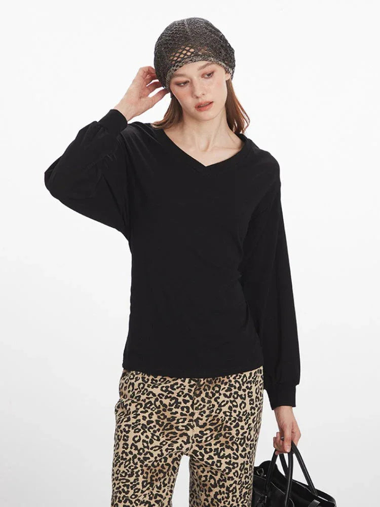 Front view of a model wearing a black V-neck long-sleeve top with voluminous sleeves and leopard print wide-leg pants.