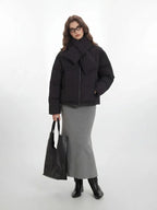 Front view of a woman in a black puffer jacket, grey skirt, and scarf