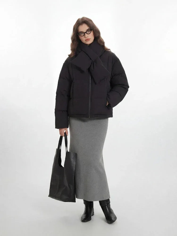 Front view of a woman in a black puffer jacket, grey skirt, and scarf