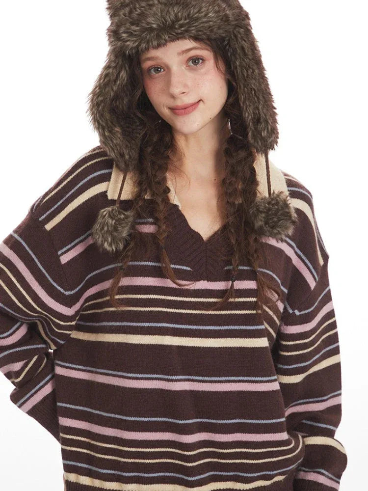 Close-up of a woman wearing a brown striped knit sweater with a v-neck and collar detail, and a brown faux fur hat with ear flaps.