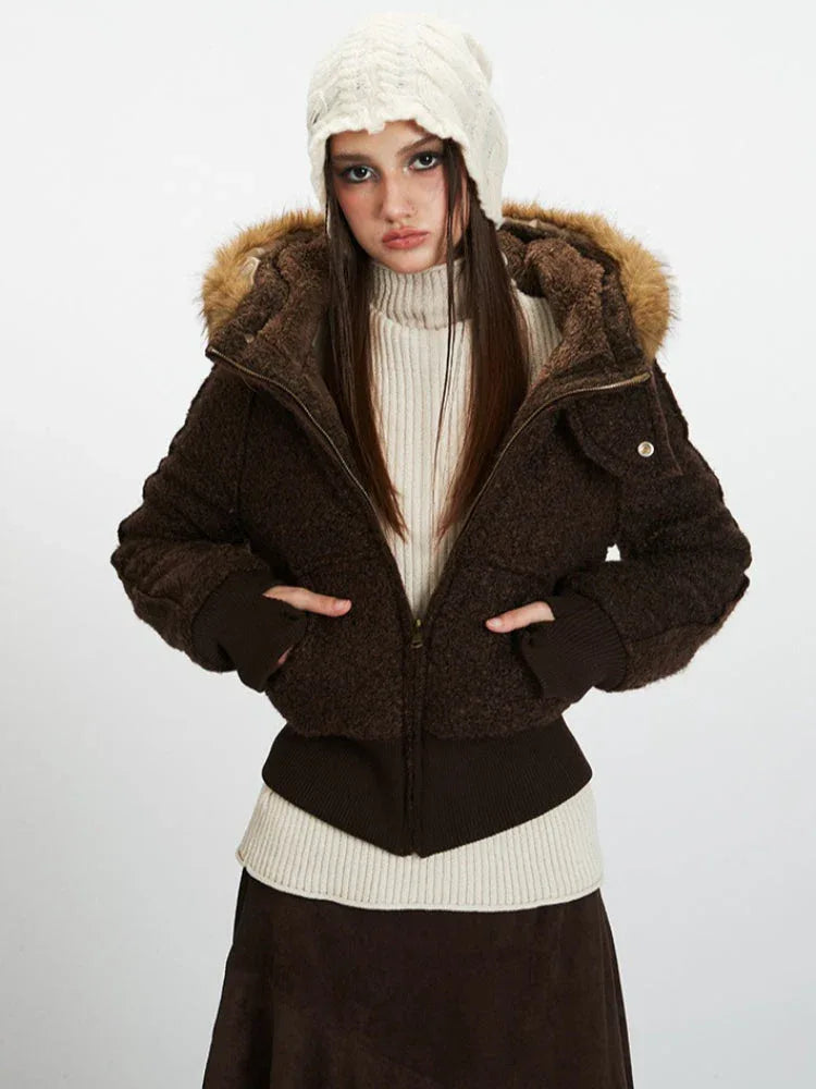 Model wearing a brown textured bomber jacket with a faux fur trimmed hood, hands in pockets