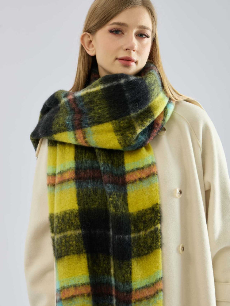woman facing forward, wearing a grey ribbed sweater and dark pants, with a colorful plaid scarf around her neck