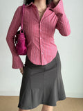 Woman holding a pink handbag and wearing a pink striped collared shirt.