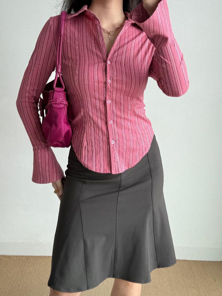 Woman holding a pink handbag and wearing a pink striped collared shirt.