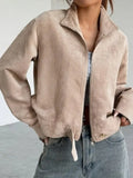 Detail shot of the front of a beige corduroy cropped jacket, showing the zip and hem detail.