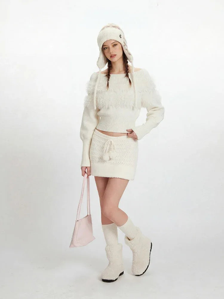 Full body shot of a woman wearing a white knit sweater and skirt set, complete with a hat and fuzzy boots.