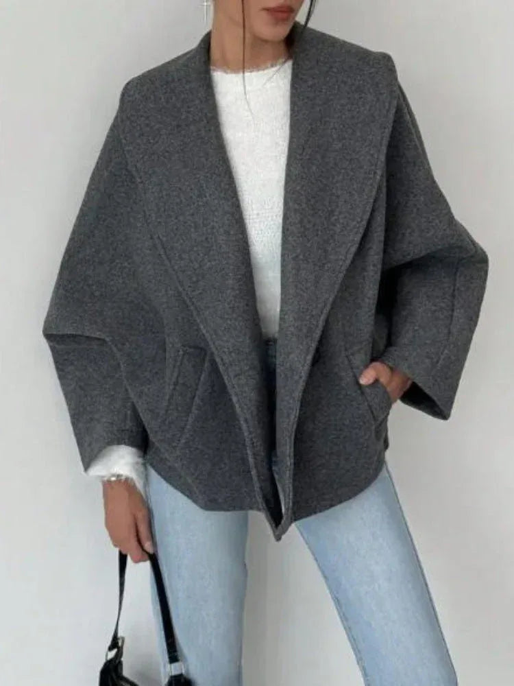 Front view of a grey wool blend oversized coat with welt pockets.