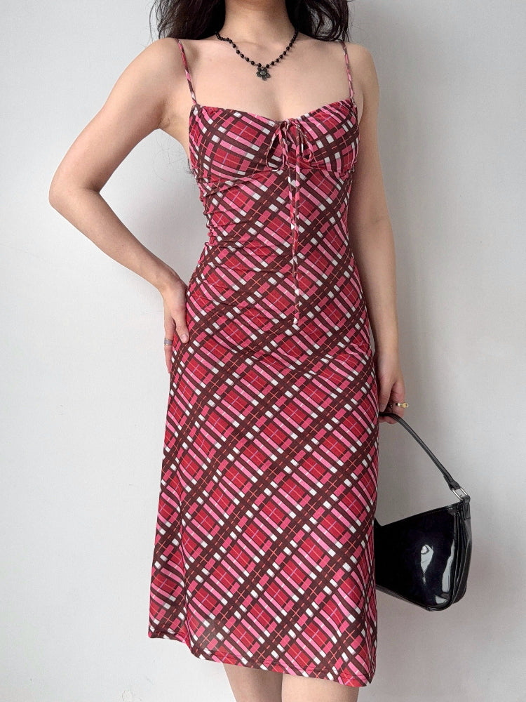 woman wearing a red and pink plaid mesh midi dress with spaghetti straps and a tie front detail