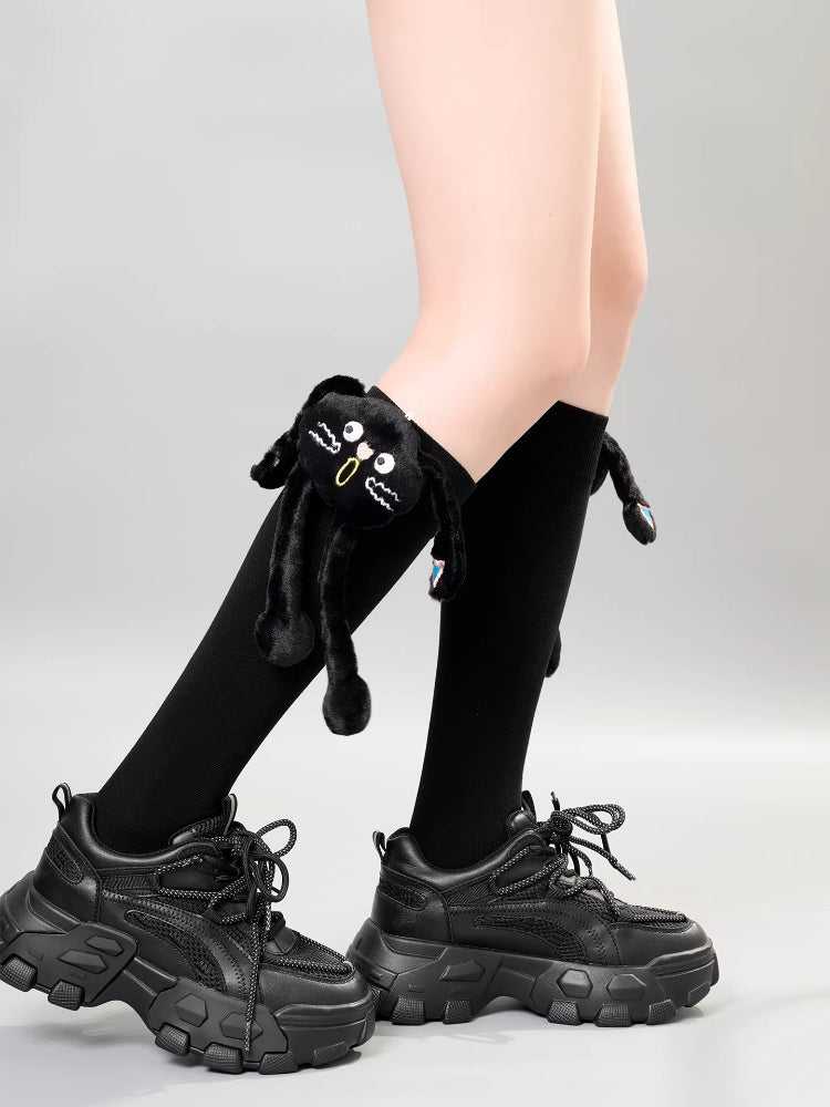 Black knee-high socks with a plush black cat design on the side, worn with black sneakers.