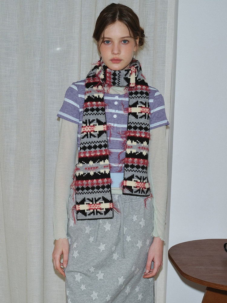 Woman wearing a patterned knit scarf with fringed edges.
