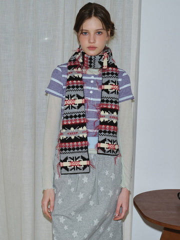 Woman wearing a patterned knit scarf with fringed edges.