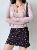Woman wearing a pink cropped knit cardigan layered over a pink camisole.