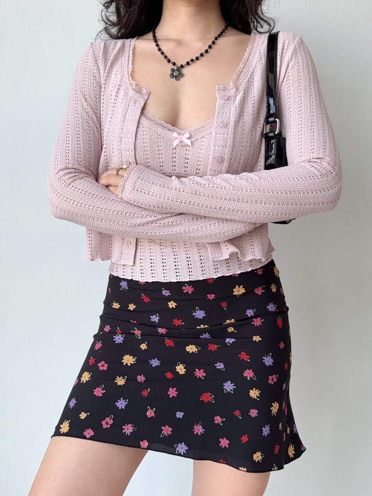 Woman wearing a pink cropped knit cardigan layered over a pink camisole.