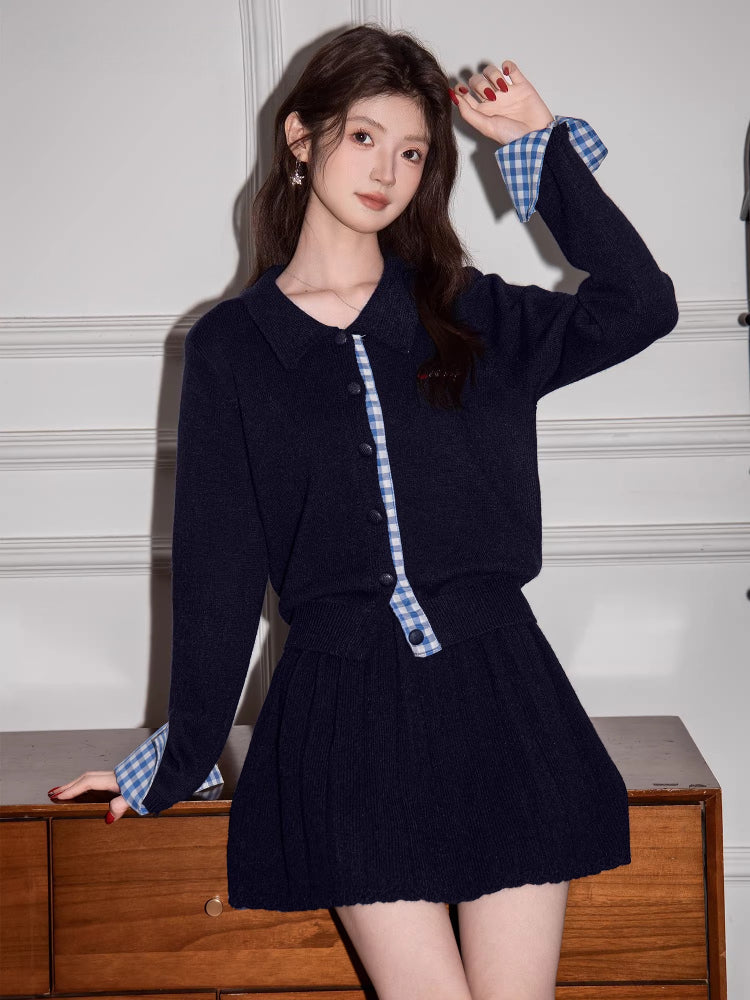 Woman wearing a navy knit cardigan with blue gingham trim and a matching pleated skirt.