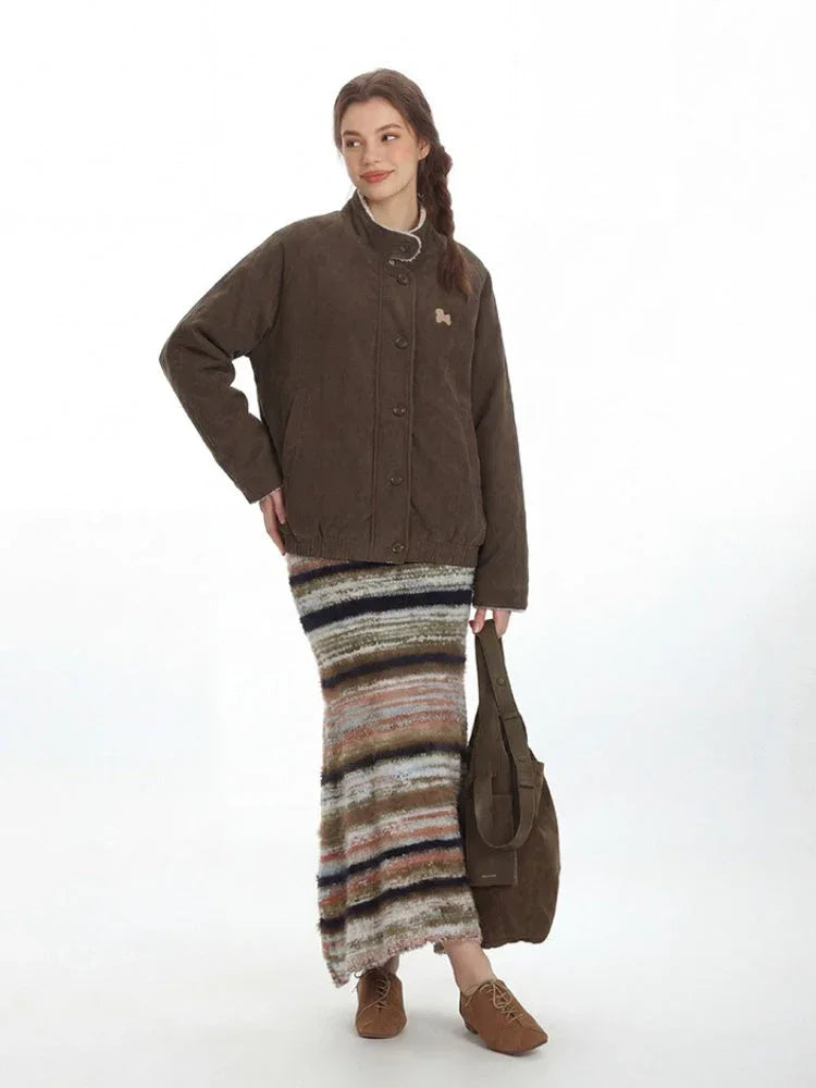 Woman wearing a brown quilted corduroy bomber jacket with a stand collar and embroidered detail
