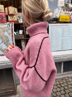 Side view of a woman in a pink knit sweater with a high turtleneck