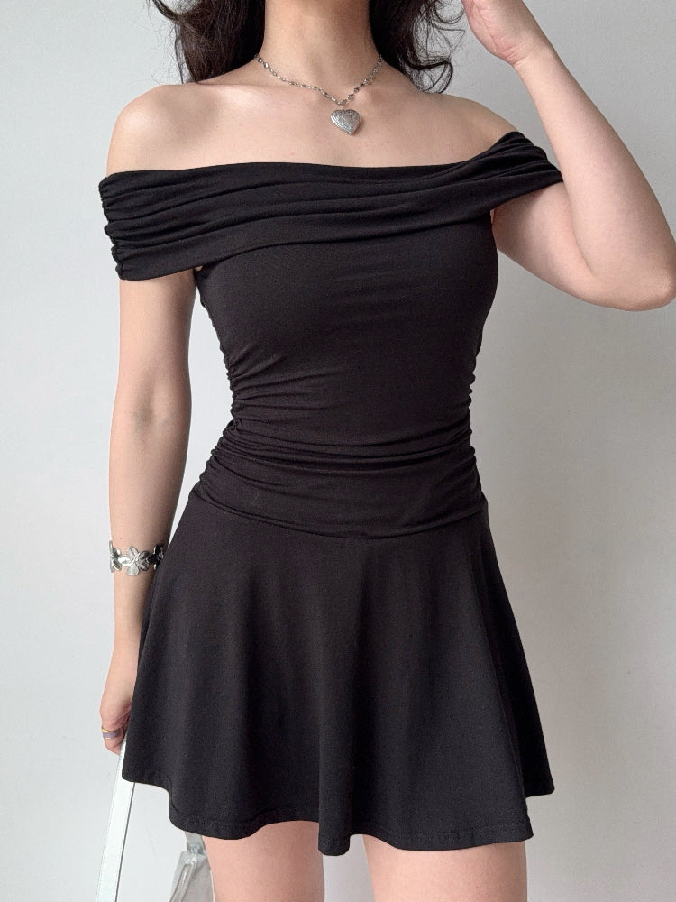 Woman wearing a black off-the-shoulder jersey knit dress with a ruched bodice and flared skirt