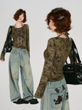 Full body shot of a woman standing, showcasing the olive green geometric print mesh top and distressed wide-leg jeans.