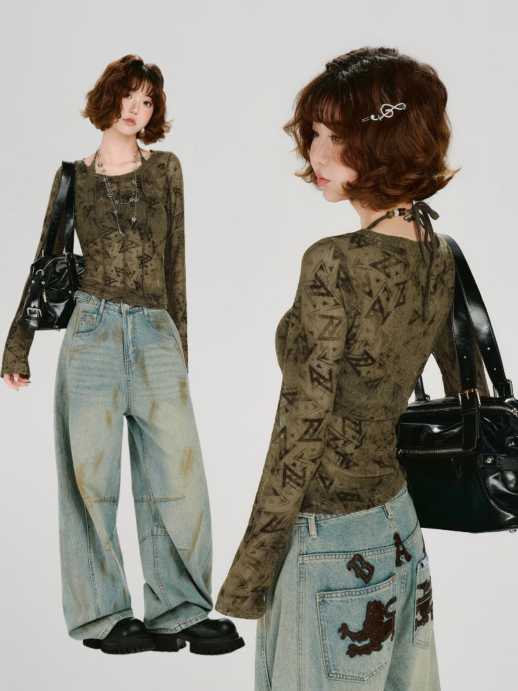 Full body shot of a woman standing, showcasing the olive green geometric print mesh top and distressed wide-leg jeans.