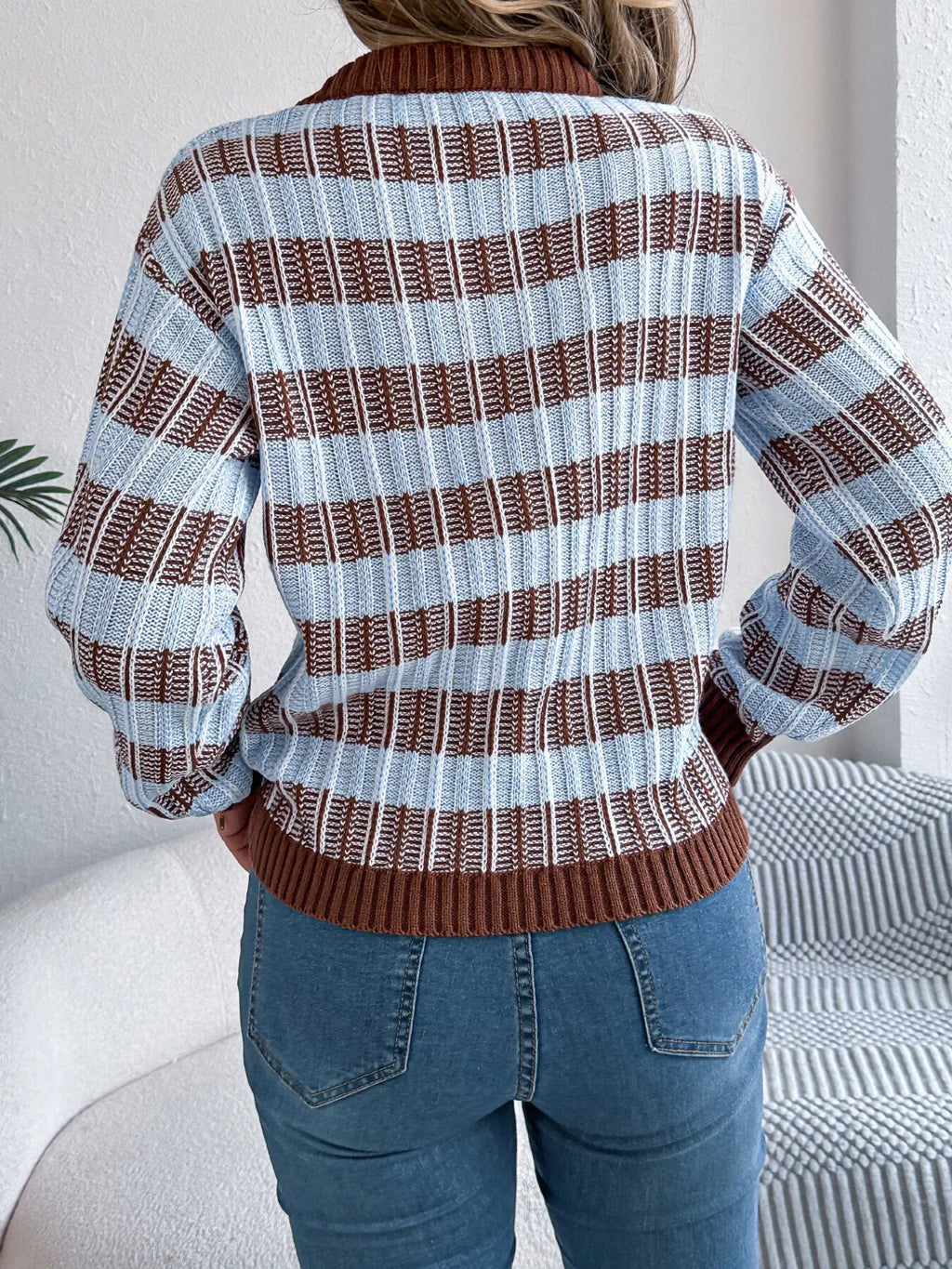Back view of a woman in a blue and brown striped knit sweater