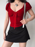 Model wearing a red velvet top and black skirt with a silver handbag