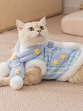 A cat wearing a blue and white striped pet vest with yellow star details and a scarf.