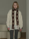 Woman wearing a cream-colored sweatshirt and a patterned scarf.