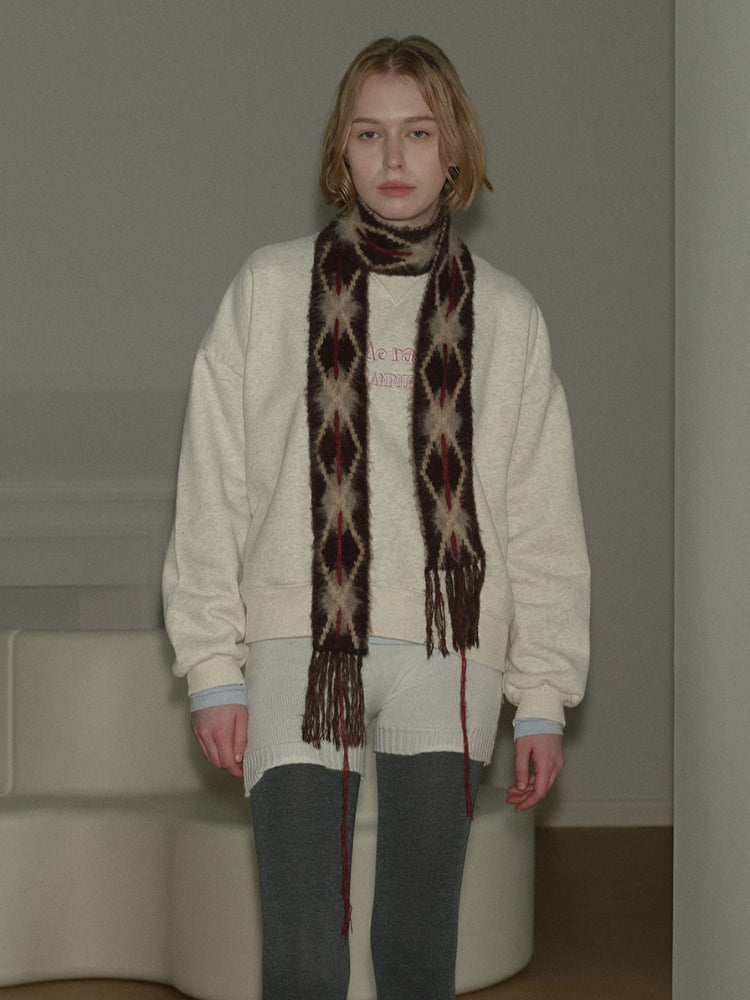 Woman wearing a cream-colored sweatshirt and a patterned scarf.