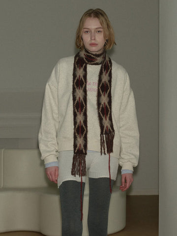 Woman wearing a cream-colored sweatshirt and a patterned scarf.