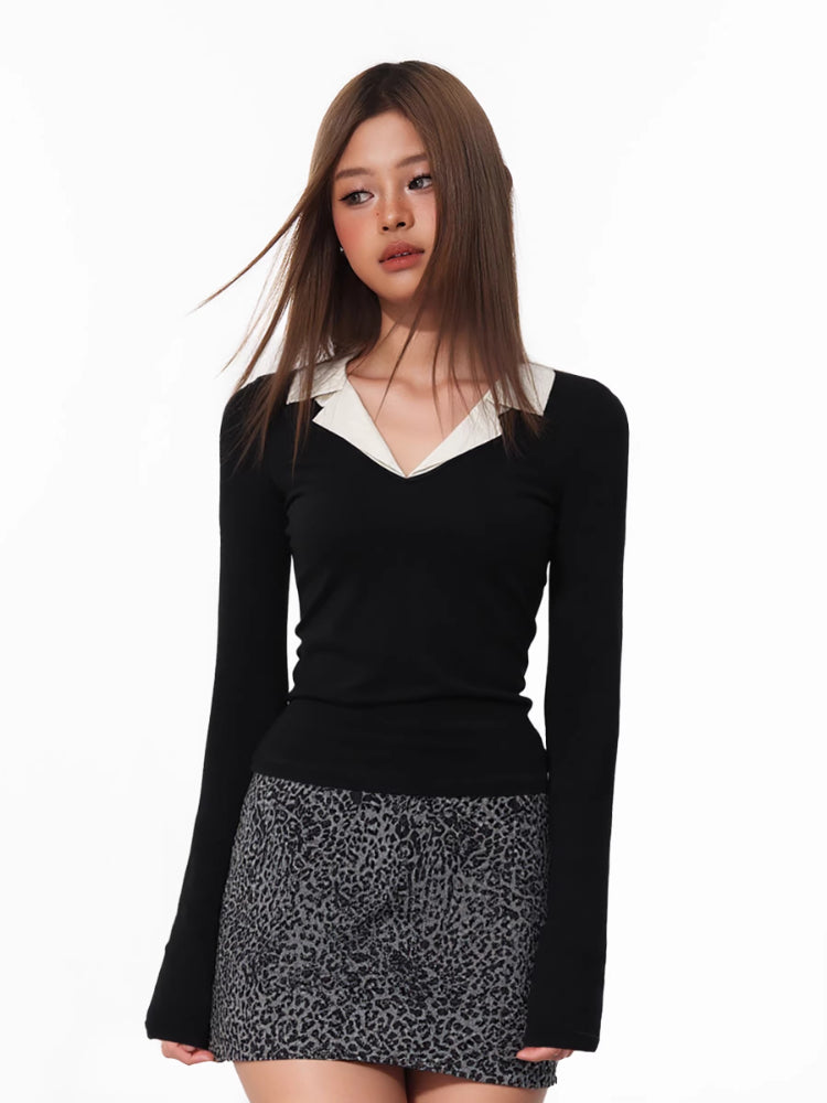 Woman in a black long-sleeve top with a white collar, posing against a white background.
