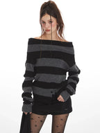 Woman wearing a grey and black striped knit sweater styled off-the-shoulder, black shorts, black patterned tights, and black boots.