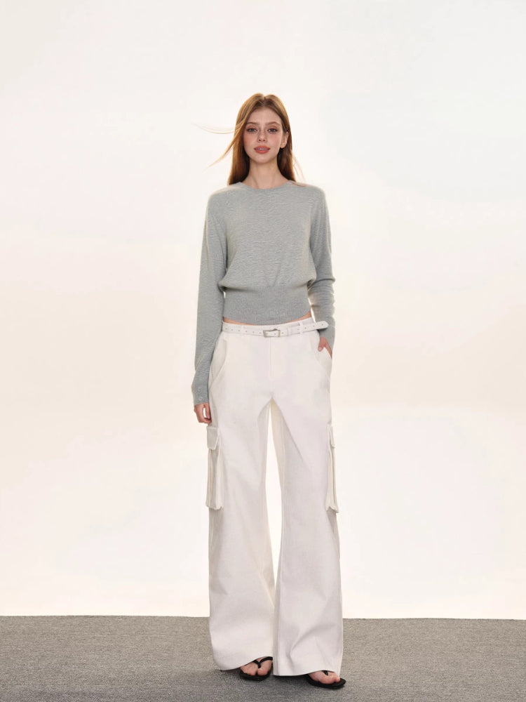 Woman wearing a light grey crew neck long sleeve cinched waist sweater