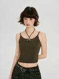 Model wearing a dark olive green halter neck crop top with a cut-out detail and metal ring accent.