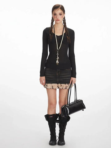 Model wearing a black long-sleeve V-neck top and a distressed denim mini skirt with faux fur trim