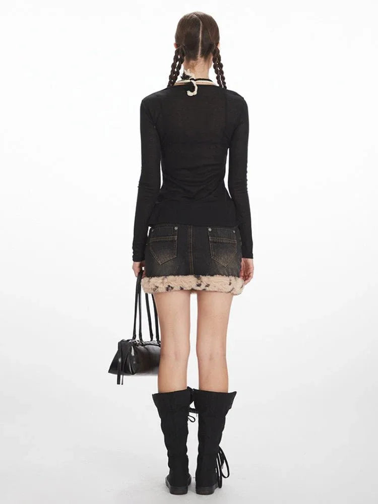 Back view of a model in a black long-sleeve top and distressed denim mini skirt with faux fur trim