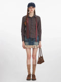 Woman wearing a plaid collared shirt, denim skirt with fur trim, and brown handbag, standing against a white background.