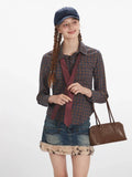 Close-up of a woman wearing a plaid shirt and a red polka dot tie, holding a brown handbag.