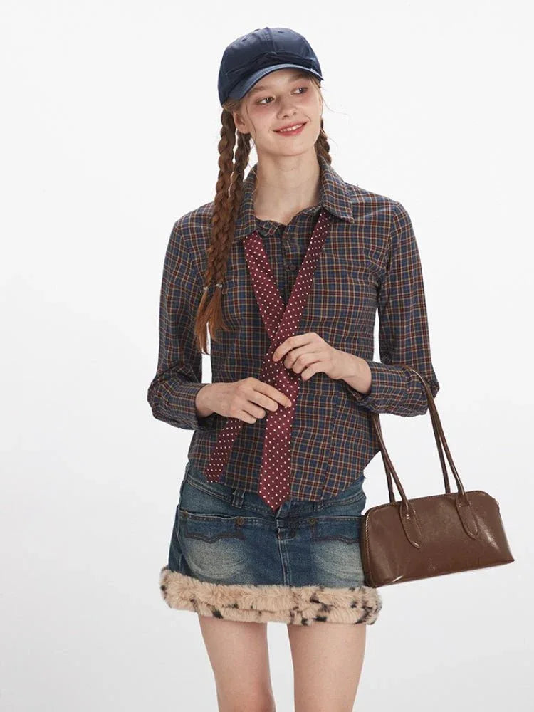 Close-up of a woman wearing a plaid shirt and a red polka dot tie, holding a brown handbag.