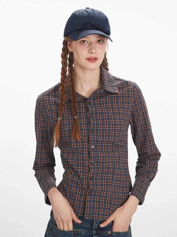 Front view of a woman wearing a plaid collared shirt, looking at the camera.